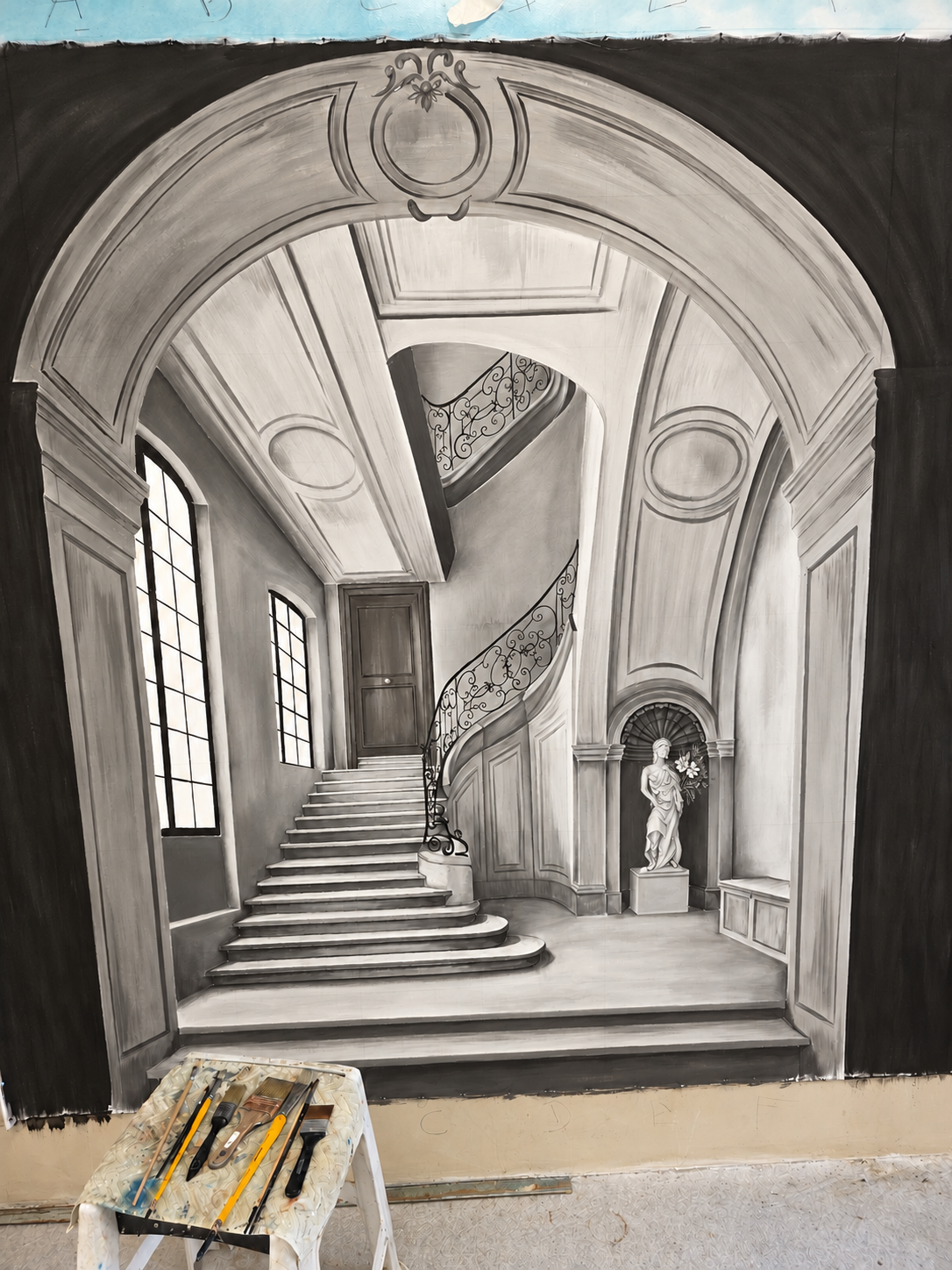 Peinture décorative en trompe l'œil représentant un escalier monumental avec moulures, colonnes et balustrade en fer forgé.